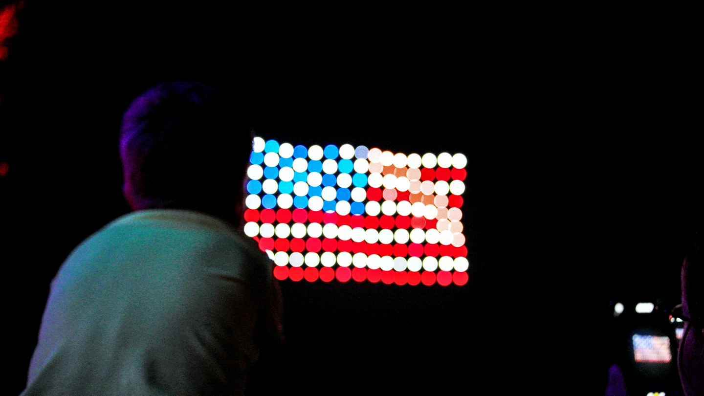 Drone light show forming an American flag over a nighttime crowd